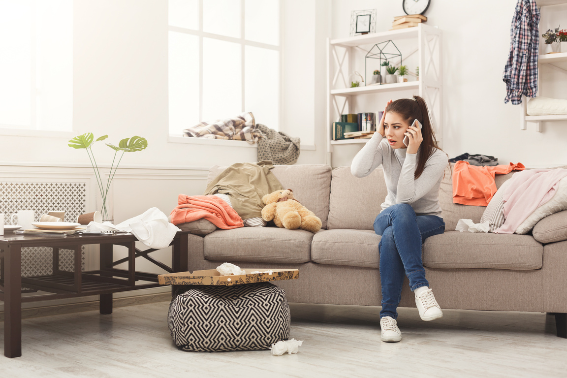 Desperate Woman Sitting on Sofa in Messy Room